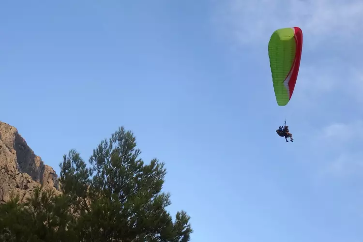 un parapente en duo, vert et jaune qui vient de prendre son envol depuis les falaises dominant saint antonin noble val
