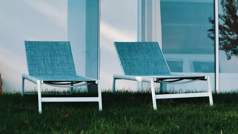 deux transats devant la façade sud du gite la cubane proche de saint-antonin noble val en occitanie ; un effet photo donne une teinte bleutée aux transats et au mur ; sur le côté gauche, on voit le reflet d'une branche d'olivier sur une baie vitrée