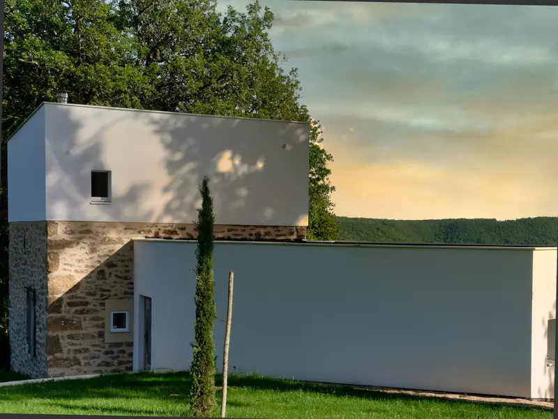 la façade nord du gite la cubane près de saint antonin noble val en occitanie ; architecture contemporaine avec le bloc central en pierre apparente et enduit sur deux niveaux, le bloc est sur un niveau en enduit blanc ; un cyprés en premier plan