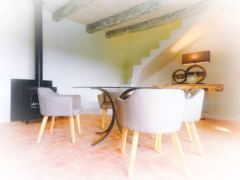 image retravaillée avec halo flou du coin salle à manger du gite de la cubane près de saint antonin noble val ; dans le fond un table baroque et l'escalier contemporain éclairé par le soleil