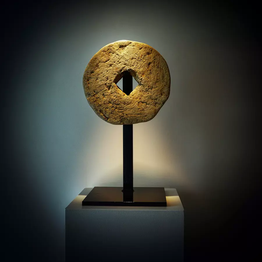 statuette circulaire, comme une meule de pierre, sur un socle en fer forgé, avec éclairage d'ambiance, témoin de la décoration raffinée du gite la cubane dans le quercy rouergue en occitanie