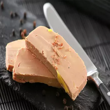 une assiette en céramique noire sur laquelle sont posées trois tranches de foie gras mi-cuit