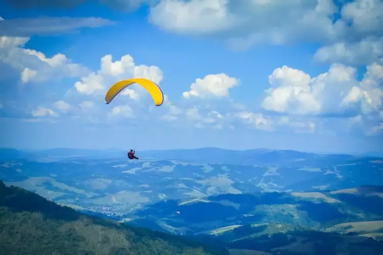 image de parapentiste survolant les paysages vallonnés du quercy et des gorges de l'aveyron
